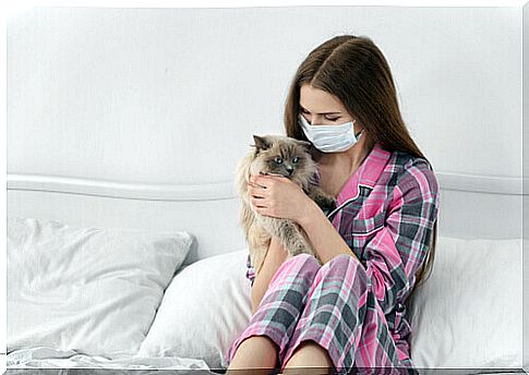 girl with mask holds a cat in her arms